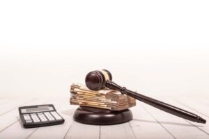 A judge's gavel and the concept of compensation represent the award of moral and financial compensation for caused damages. This involves lawyer services, workers' rights protection, and efforts to raise wages.
