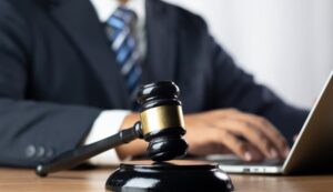 Justice, law, attorney, and court judge concept. A judge holds a gavel, preparing to strike the sounding block in the courtroom.