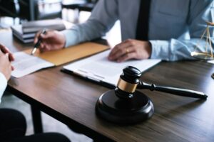 Legal counsel presents a signed contract to the client with a gavel and legal books in the background, symbolizing justice and the lawyer's role.