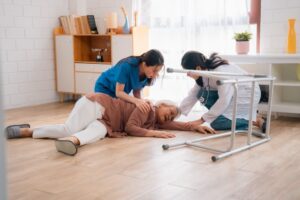 A caregiver assists a senior patient who has fallen at home. Emergency health insurance provides crucial support. A female nurse tends to the injury. 