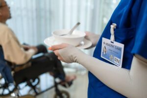 Close-up of a woman nurse's hands at a nursing home, caring for a disabled senior elderly man in a wheelchair. 