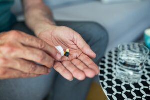 A stressed senior man takes an antidepressant pill with water, showing the act of self-medication and the emotional impact of antidepressant drugs. 