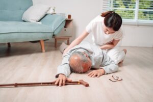 An Asian woman, either the daughter or granddaughter, helping an elderly man from falling in the living room at home.