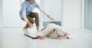 A nurse helps an elderly woman on the floor, providing medical care for her injury. In this emergency situation, the caregiver attends to the patient's pain and needs.