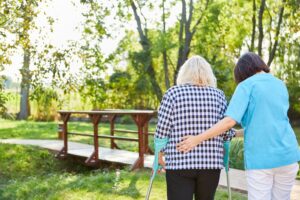 Therapist or nurse assisting senior woman in learning to walk. 