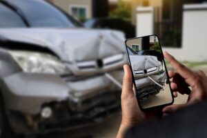 Man holding smartphone and take photo of car accident call for help damage to car after accident