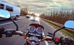 A motorcyclist in front of a car on the road