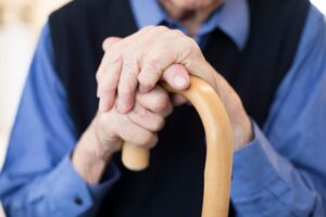 Senior Man's Hands Holding Walking Cane in Nursing Home