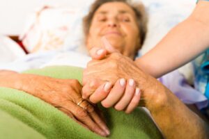 Health care nurse holding elderly lady's hand with caring attitude.