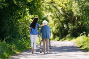 Nurse and elderly woman enjoying a warm day in nursing home, public park.