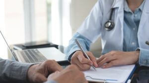 Doctor filling medical insurance claim form at medical clinic