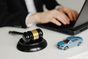 Car Accident Attorney working on laptop with Judge's hammer and toy car on the table