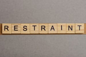 Text the word restraint from brown wooden small letters