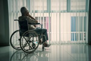 Rear view of a senior man sitting in the wheelchair while looking out the window